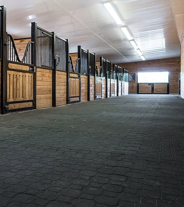 Stable aisle with wooden stall fronts and a ceiling finished with Trusscore panels.