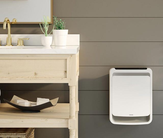 Fan heater mounted on a bathroom wall, next to a wooden sink.