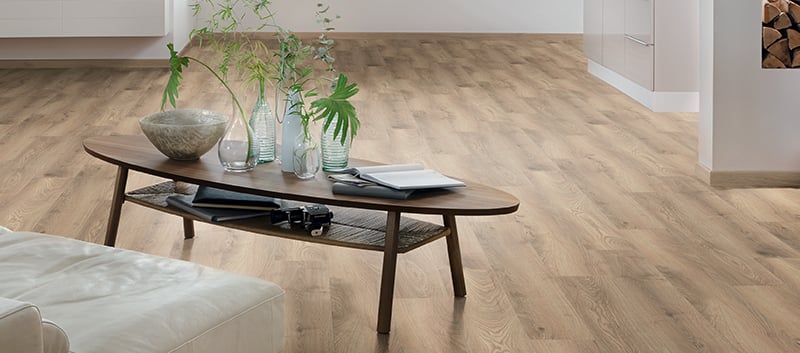 Beau plancher stratifié de couleur brun dans un salon avec table basse et divan blanc en cuir