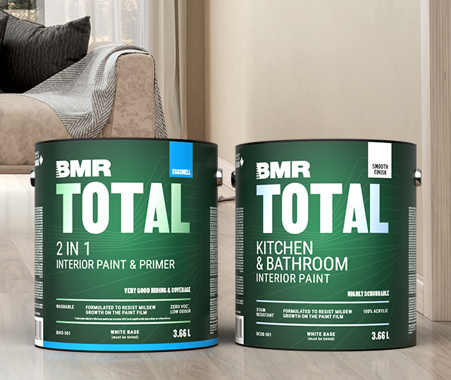 Gallons of BMR paint placed on the floor of a living room, with a beige sofa visible in the background.