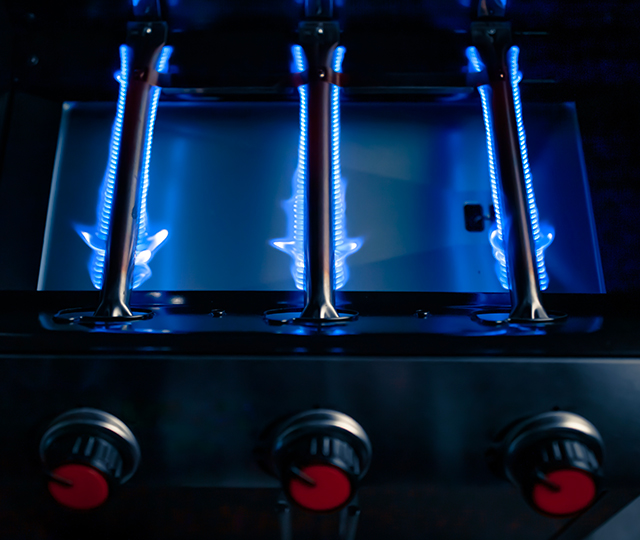 Br&ucirc;leurs de barbecue au gaz allum&eacute;s montrant des flammes bleues align&eacute;es.