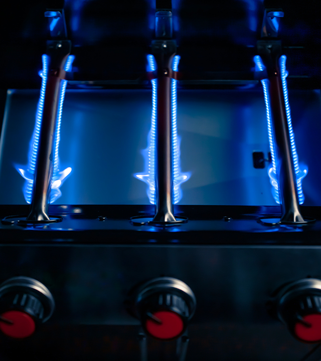 Br&ucirc;leurs de barbecue au gaz allum&eacute;s montrant des flammes bleues align&eacute;es.