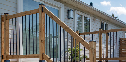 Balustrade de patio en bois avec balustres m&eacute;talliques noirs, install&eacute;e devant une maison avec rev&ecirc;tement ext&eacute;rieur clair.