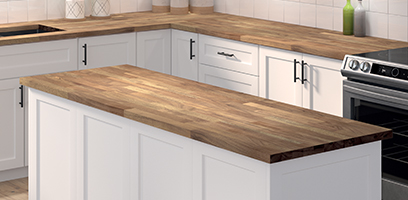 &Icirc;lot de cuisine avec comptoir en bois massif et armoires blanches de style moderne, dans une cuisine lumineuse et &eacute;pur&eacute;e.