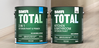 Two dark green BMR Total paint cans (3.6 L) for interior use — 2-in-1 paint and primer, including a kitchen and bathroom formula — placed on a wooden floor.