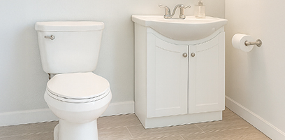 Salle de bain minimaliste avec toilette blanche et meuble-lavabo blanc &agrave; deux portes, robinet chrom&eacute; et porte-papier mural, sur plancher en c&eacute;ramique beige.