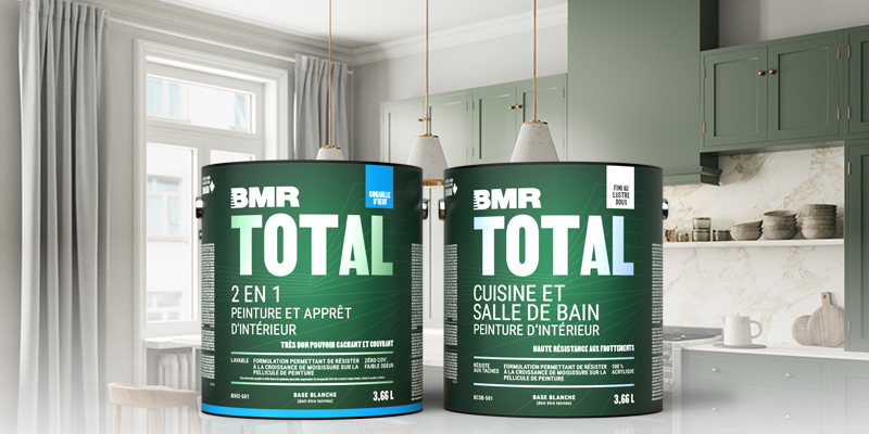 Deux gallons de peinture int&eacute;rieure BMR Total, dont une peinture et appr&ecirc;t 2 en 1 et une peinture cuisine et salle de bain, pr&eacute;sent&eacute;s dans une cuisine moderne aux armoires vertes.