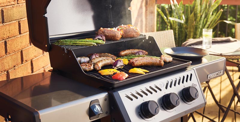 Sausages and vegetables cooking on a gas barbecue
