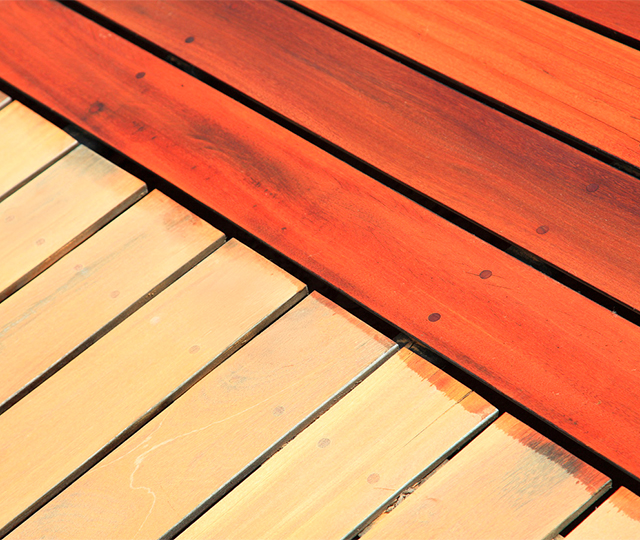 Application uniforme de teinture sur planches de terrasse en bois à l’aide d’un pinceau et d’un bac de produit